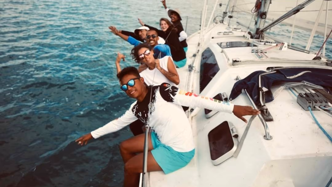 Crew celebrating on the rail of a sailboat
