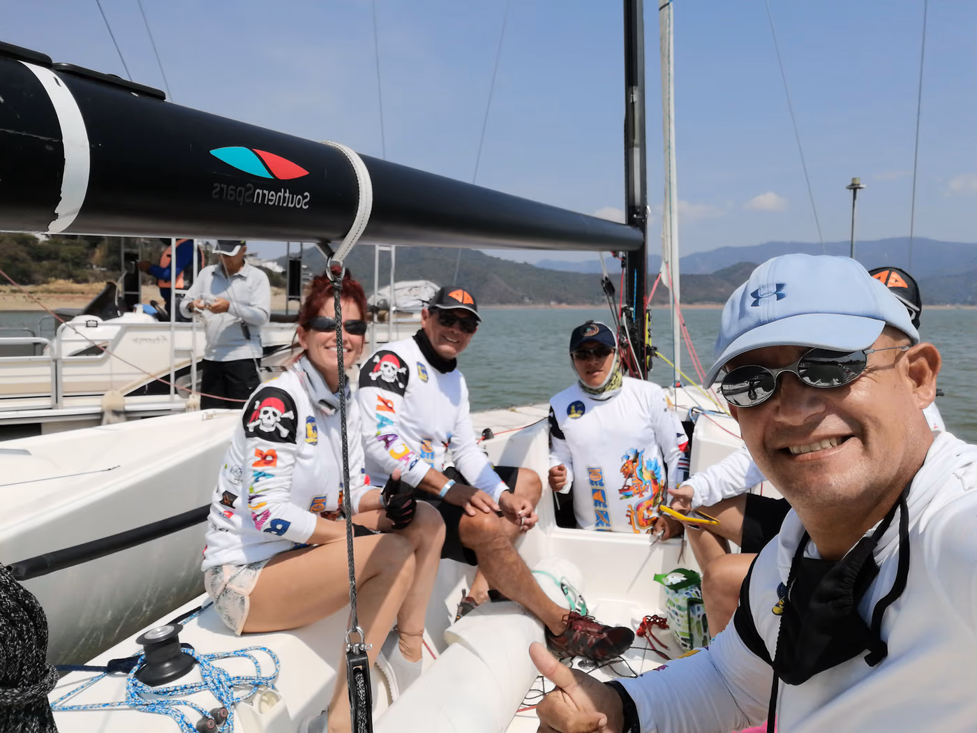 Equipo de regata sonriendo a bordo de un velero antes de salir